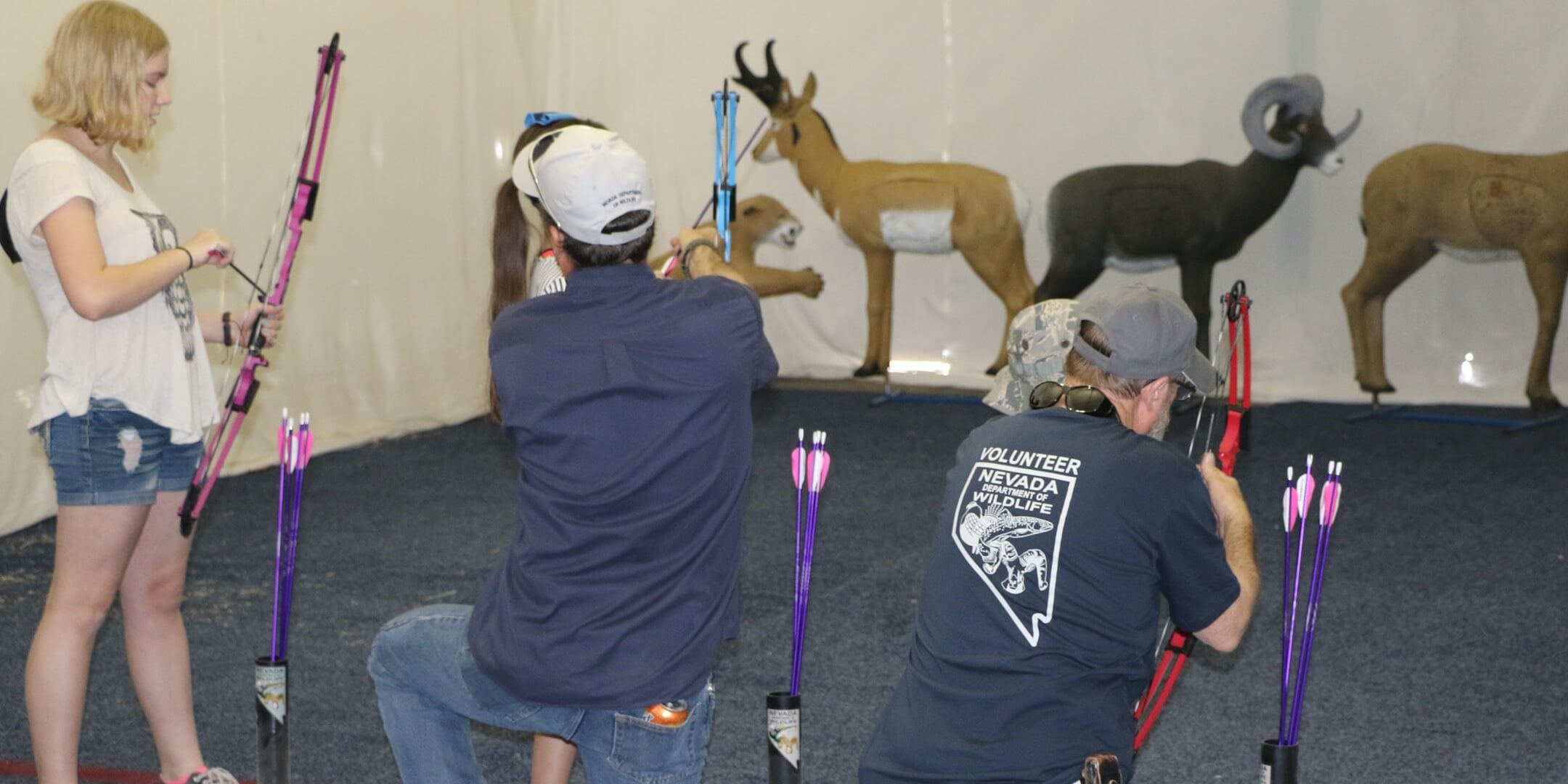 Two NDOW Volunteers set up bows and arrows for students in a NDOW archery class